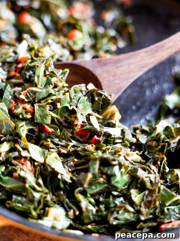 Wooden spoon scooping collard greens in a skillet.