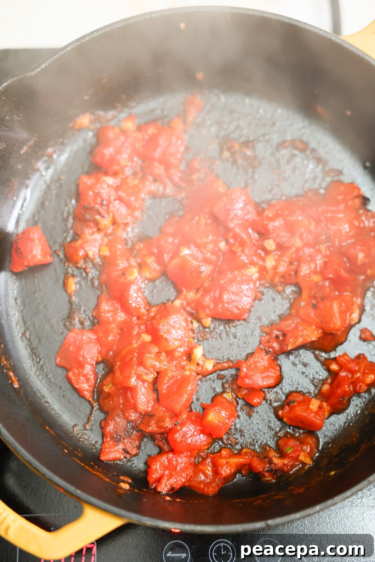 Tomatoes sauteing in a skillet.