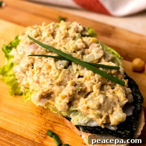 Vegan chickpea salad on toast on a wooden cutting board.