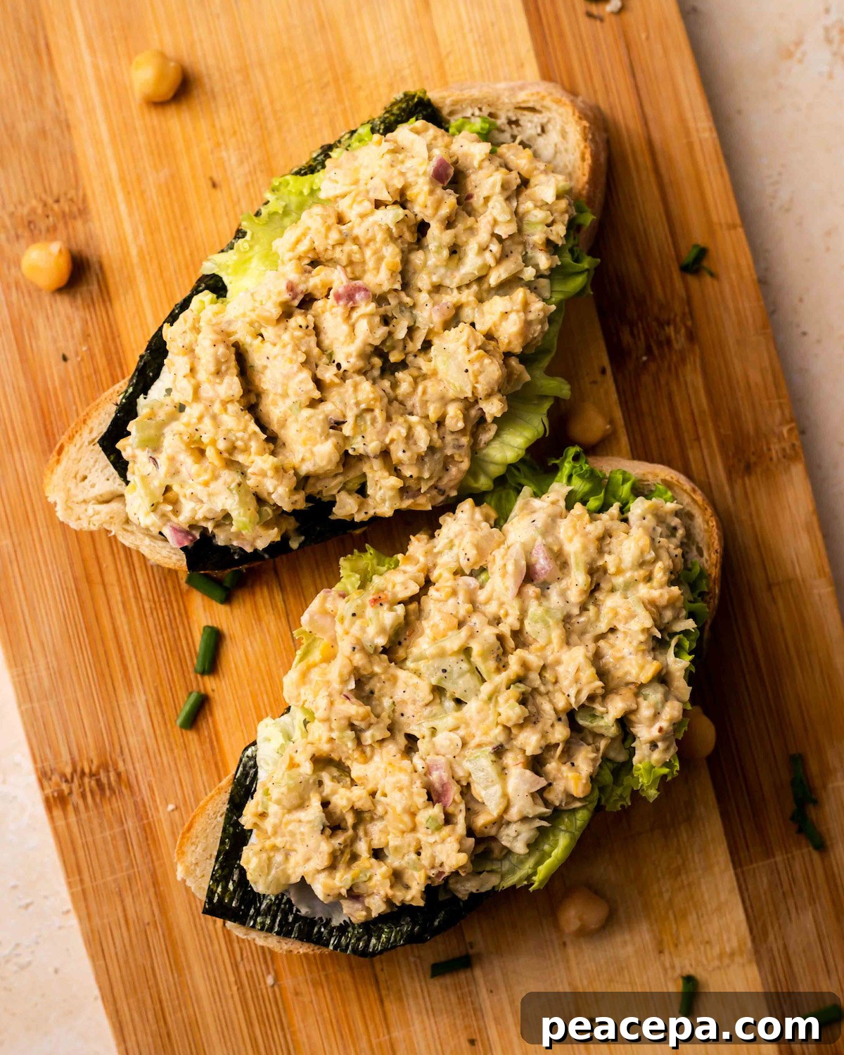 Two slices of vegan chickpea tuna salad on a wooden cutting board.