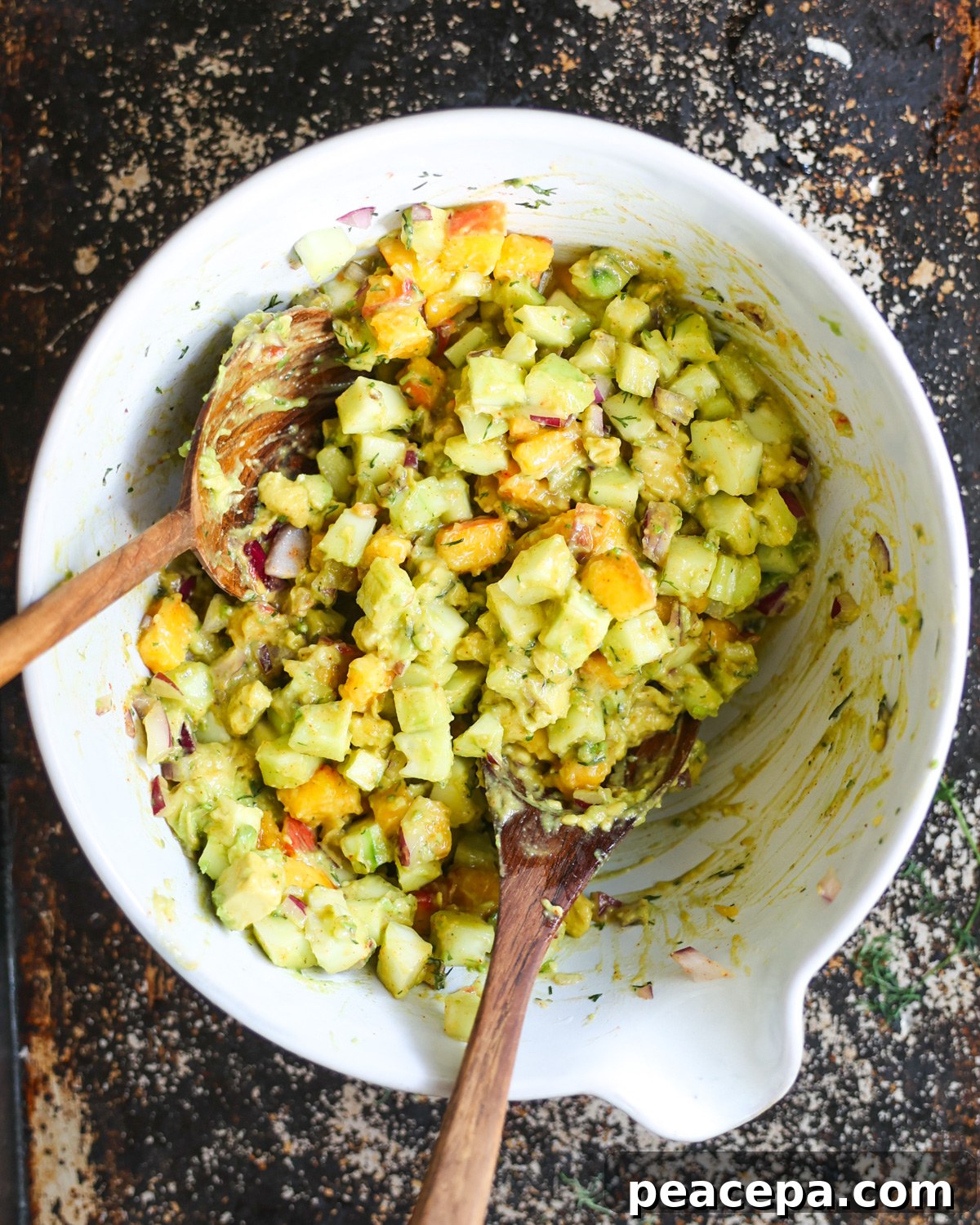 overhead of cucumber avocado salad in mixing bowl