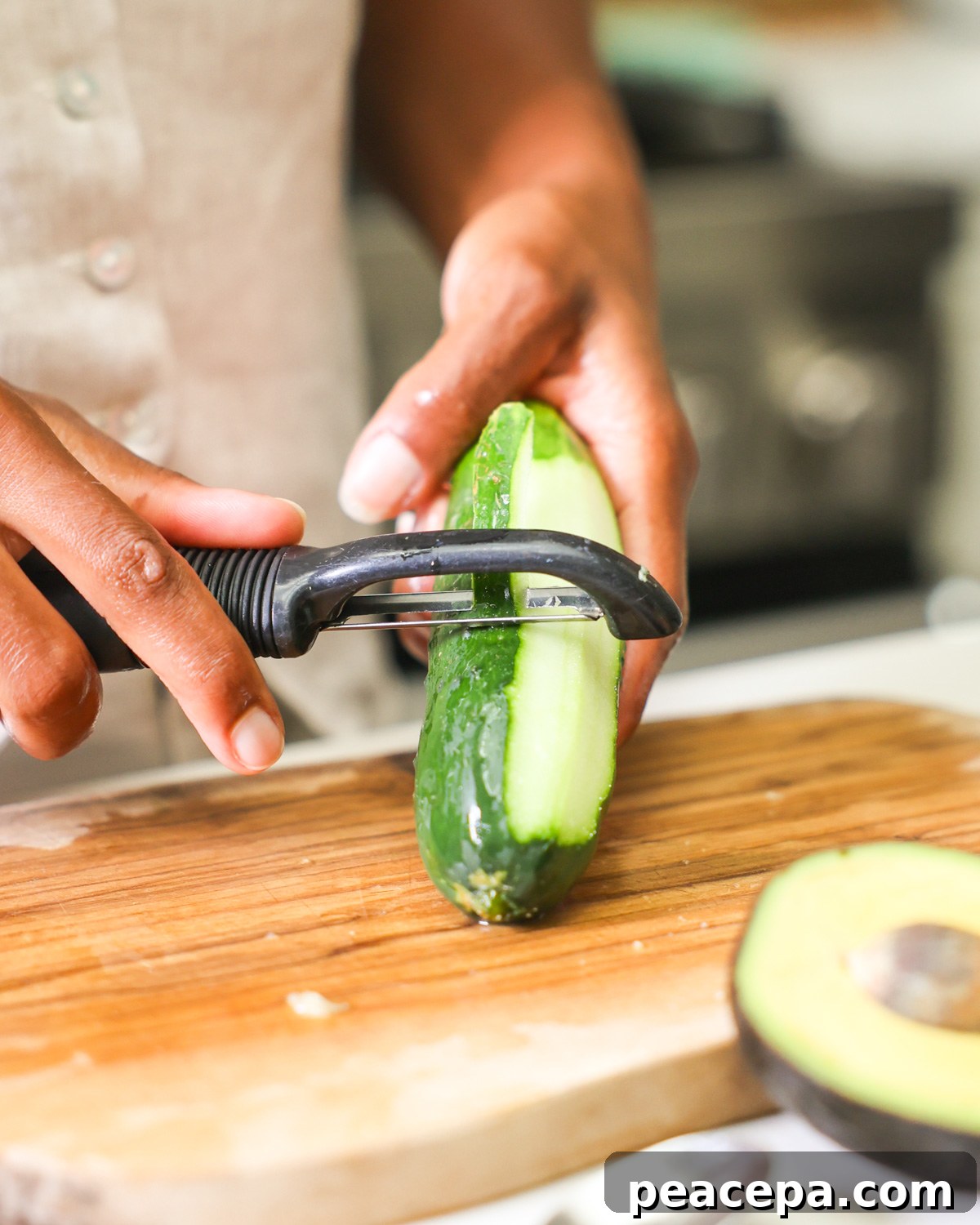 brown hands peeling a cucumber