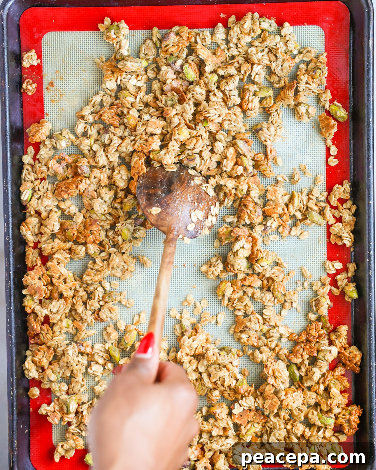 stirring granola on baking sheet