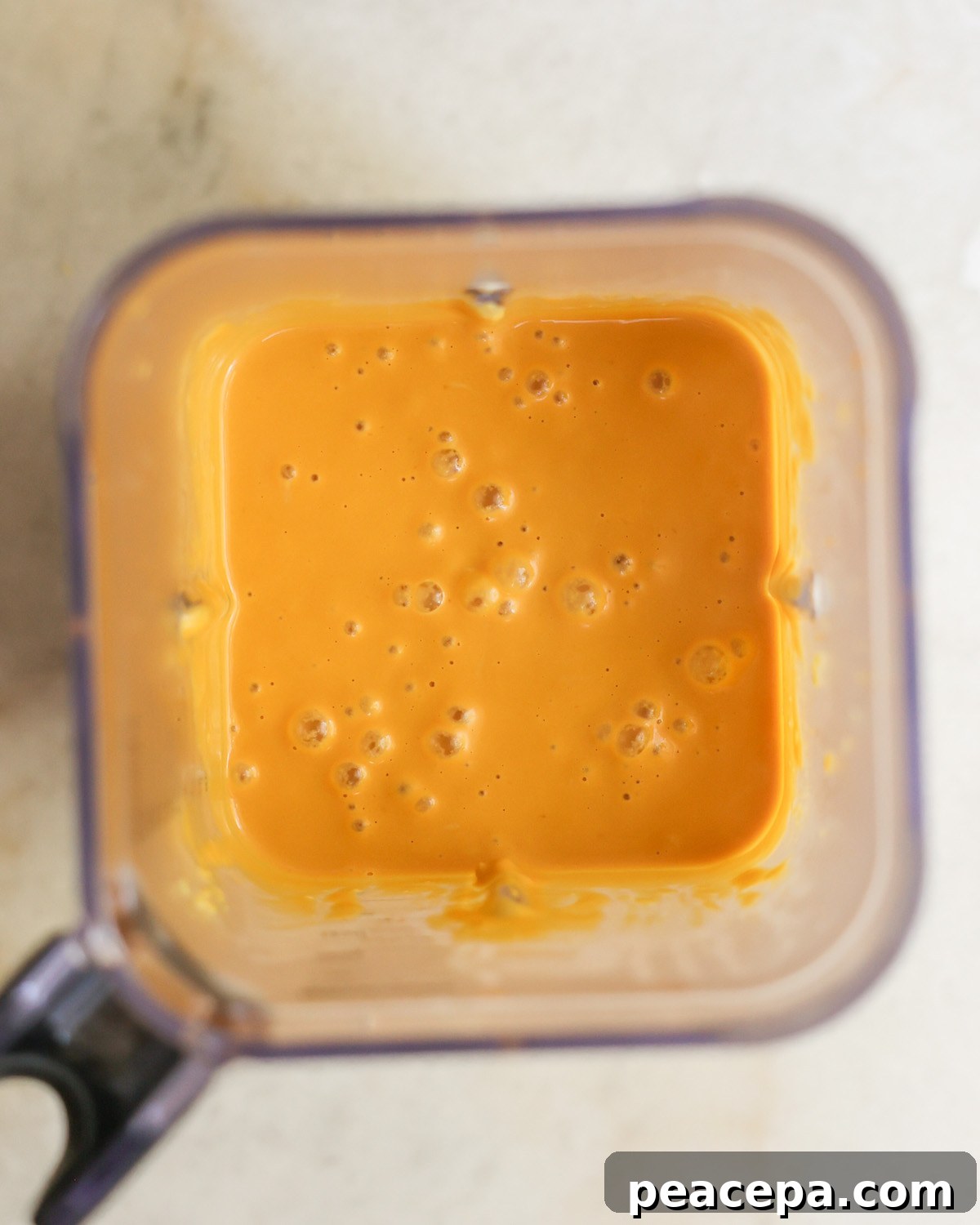 An overhead shot of a blender of pureed butternut squash mac and cheese sauce.