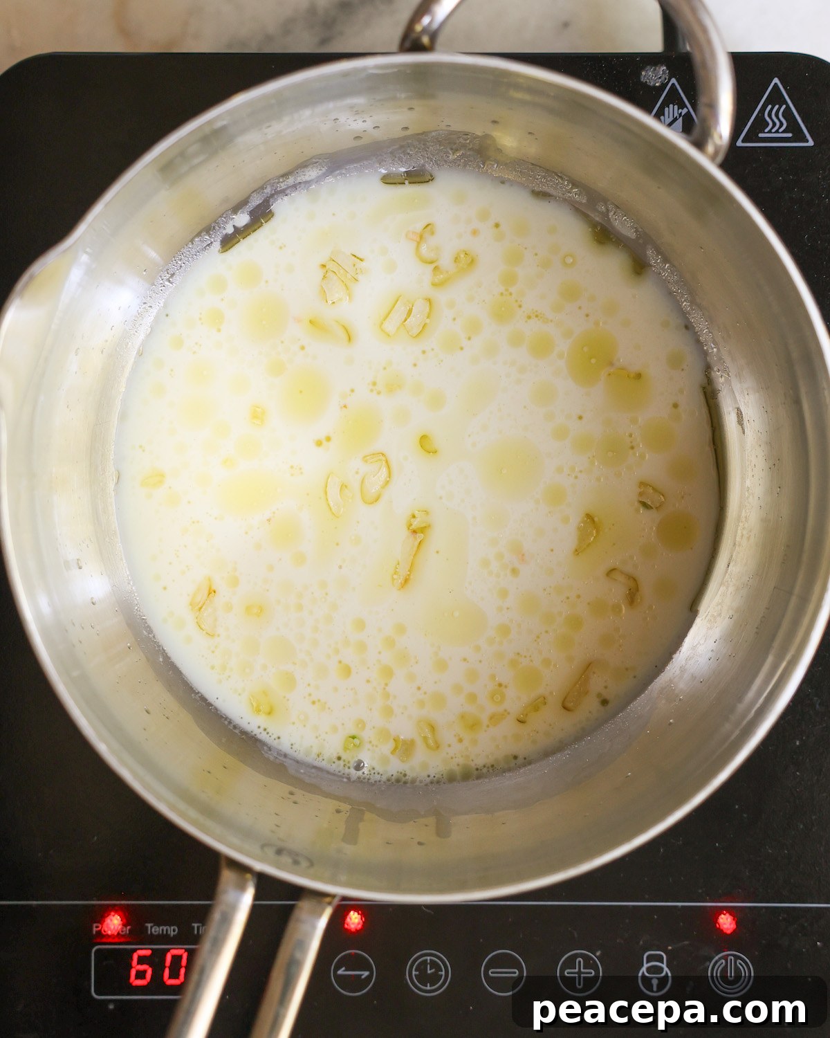 An overhead shot of milk, garlic, and vegan butter simmering in a pot.