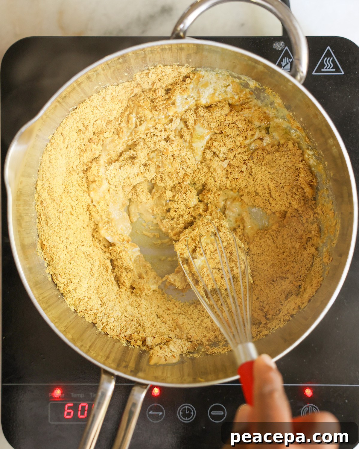 Whisking a pot of nutritional yeast with the milk and seasonings.