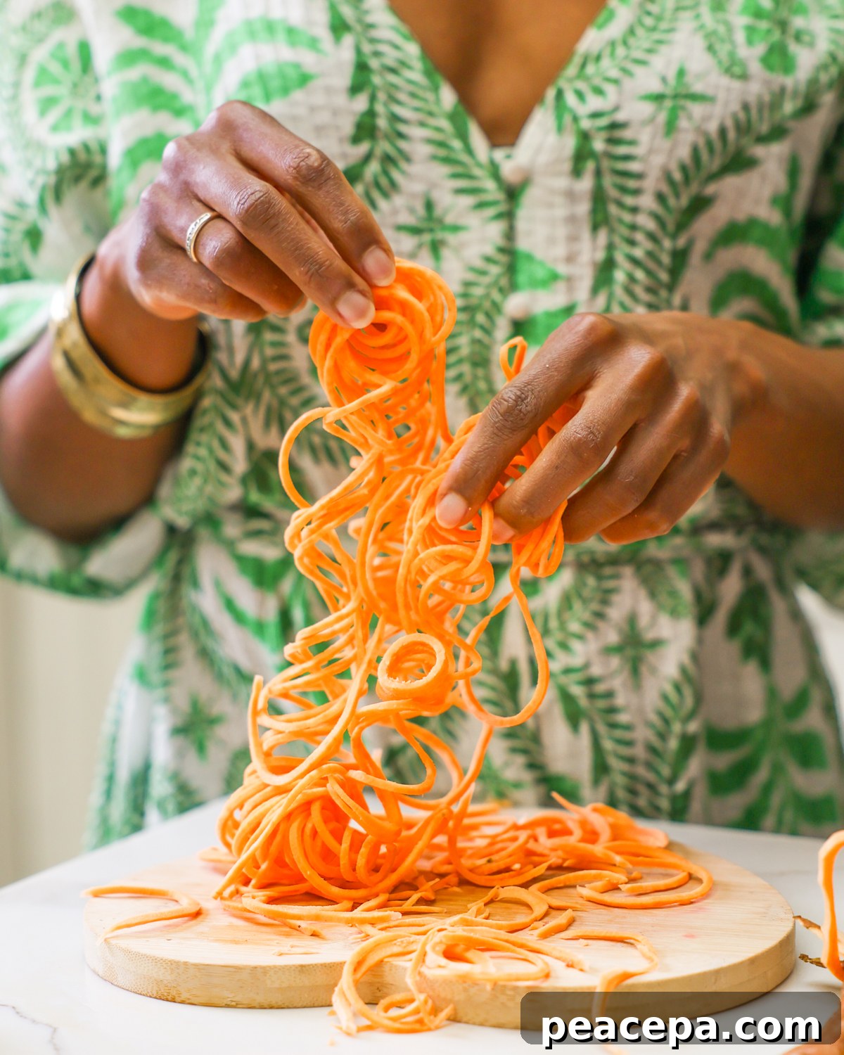 holding long strands of spiralized sweet potato noodles