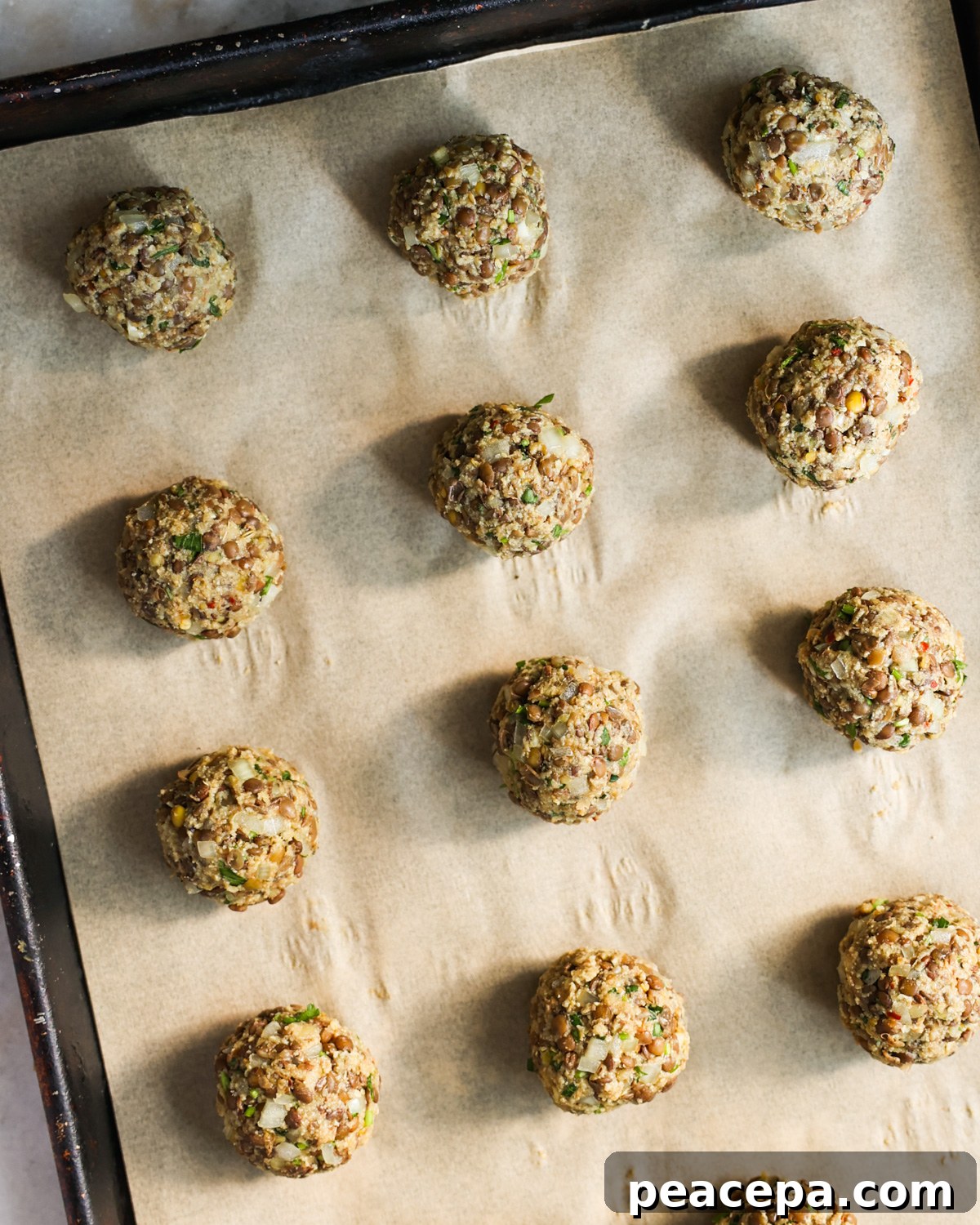 Uncooked vegan meatballs on baking sheet.