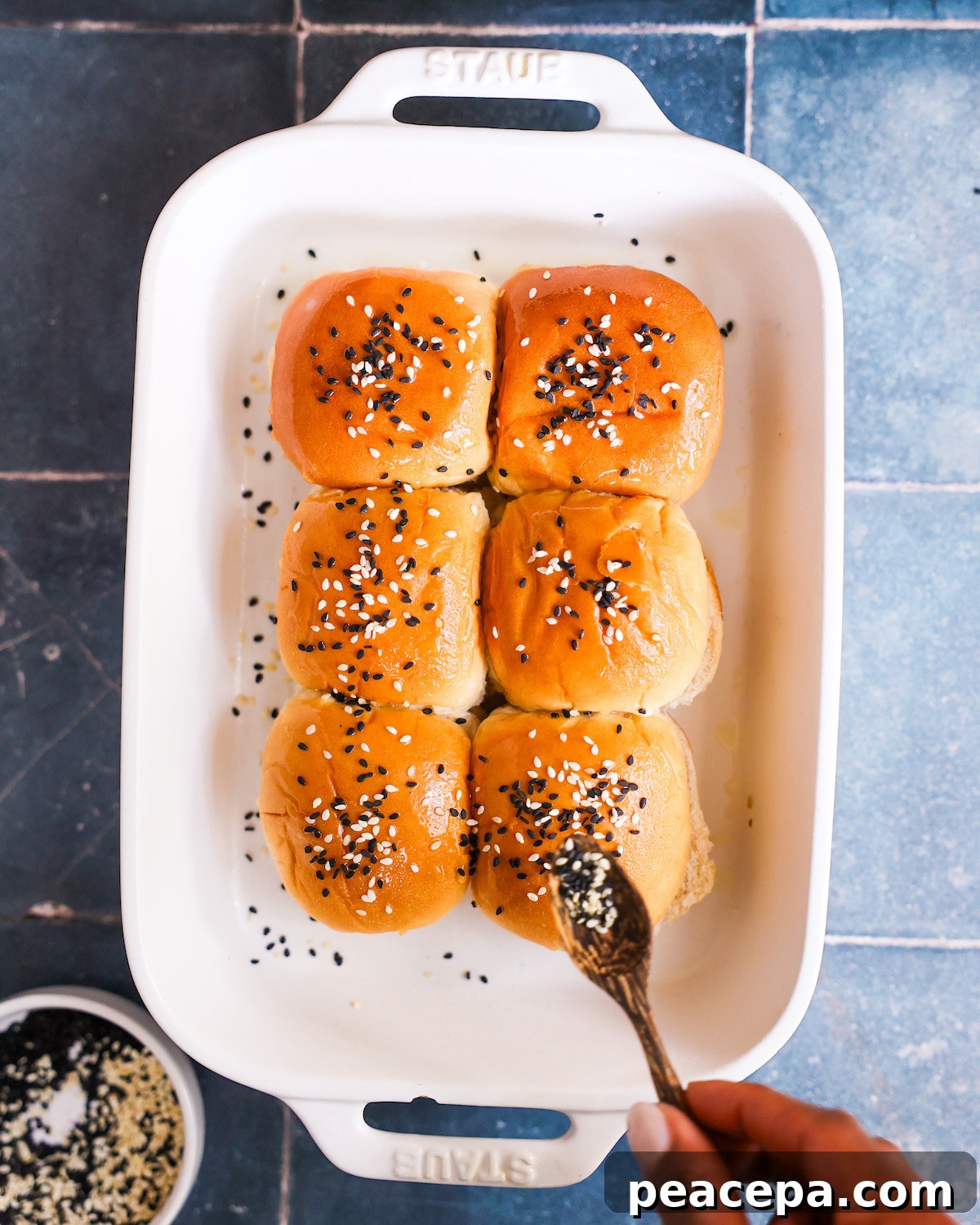 sprinkling sesame seeds on buns for veggie sliders