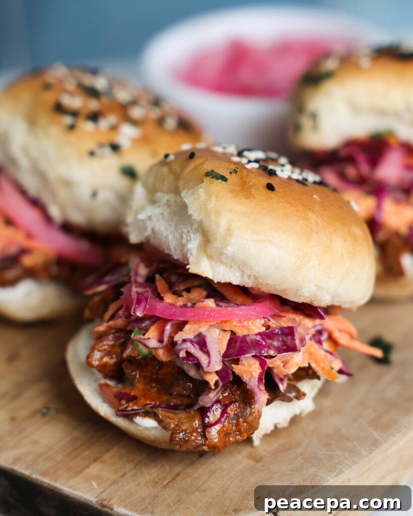 A close up of mushroom veggie sliders on a wooden cutting board with pickled red onions.