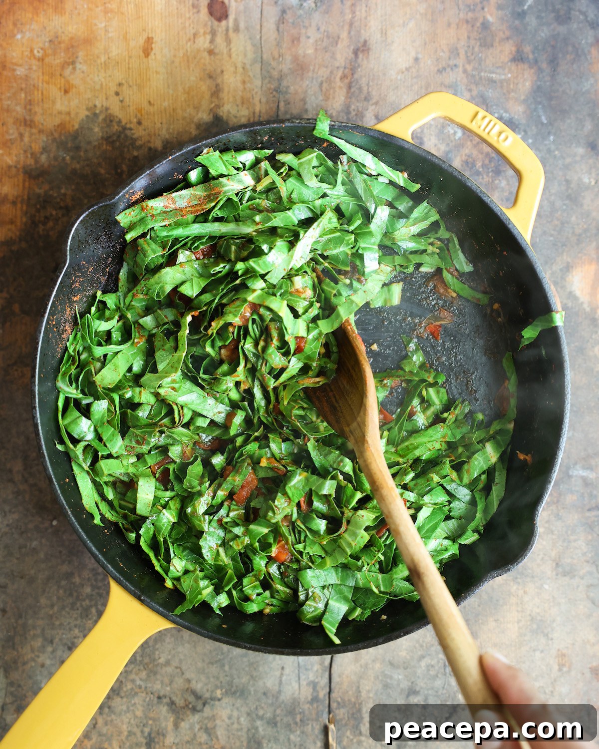 Bright green collard greens sautéing in a yellow skillet.