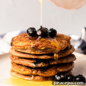 Drizzling a stack of the vegan blueberry pancakes with maple syrup.