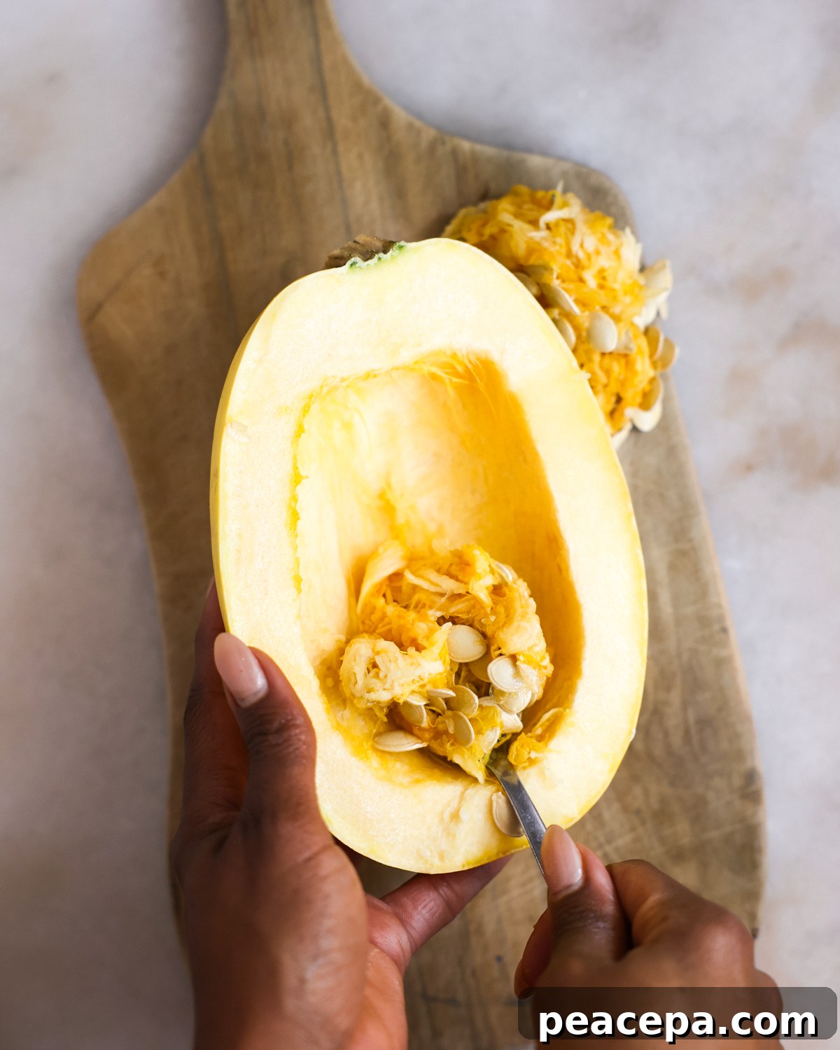 overhead scooping seeds out of spaghetti squash