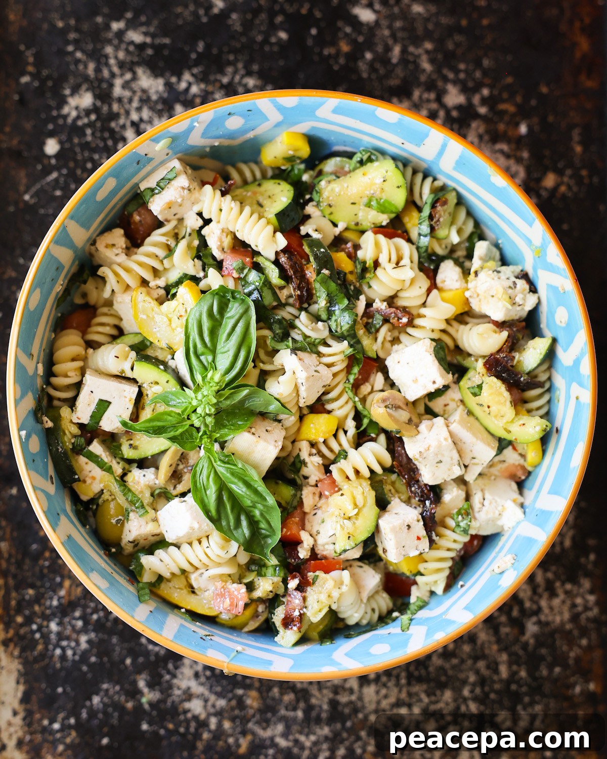 An overhead shot of a bowl of Mediterranean pasta salad with basil.