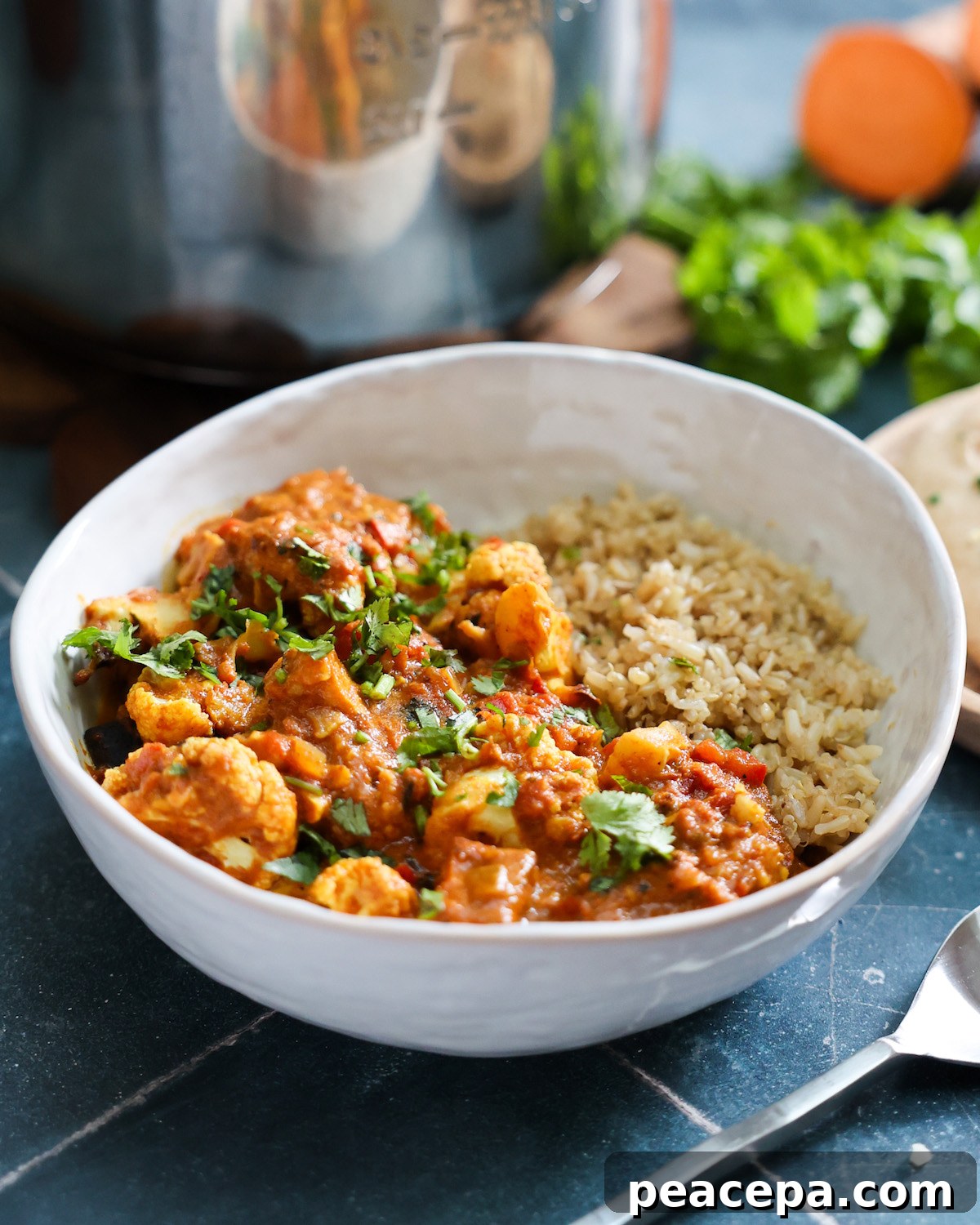 Tempeh vegan tikka masala in a white bowl on a blue tile counter.