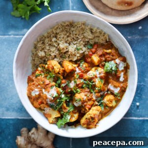 Overhead of vegan tempeh tikka masala in a white bowl on a blue tile counter.