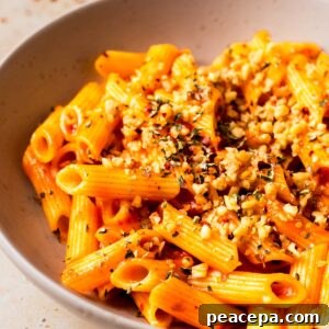 An up-close angled shot of a bowl of arrabbiata sauce on penne.