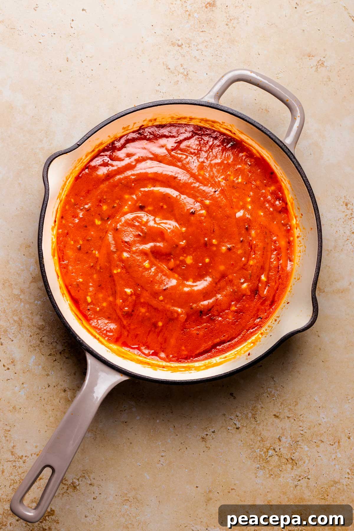 An overhead shot of a large skillet of simmered arrabbiata sauce.
