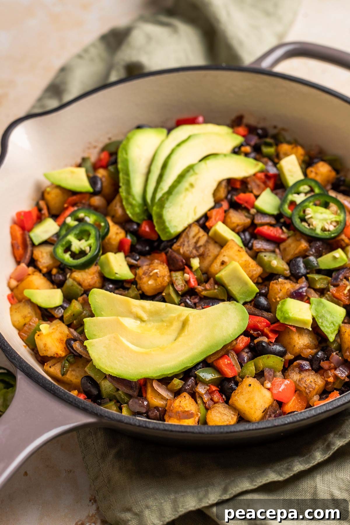 sweet potato breakfast hash in skillet garnished with avocado