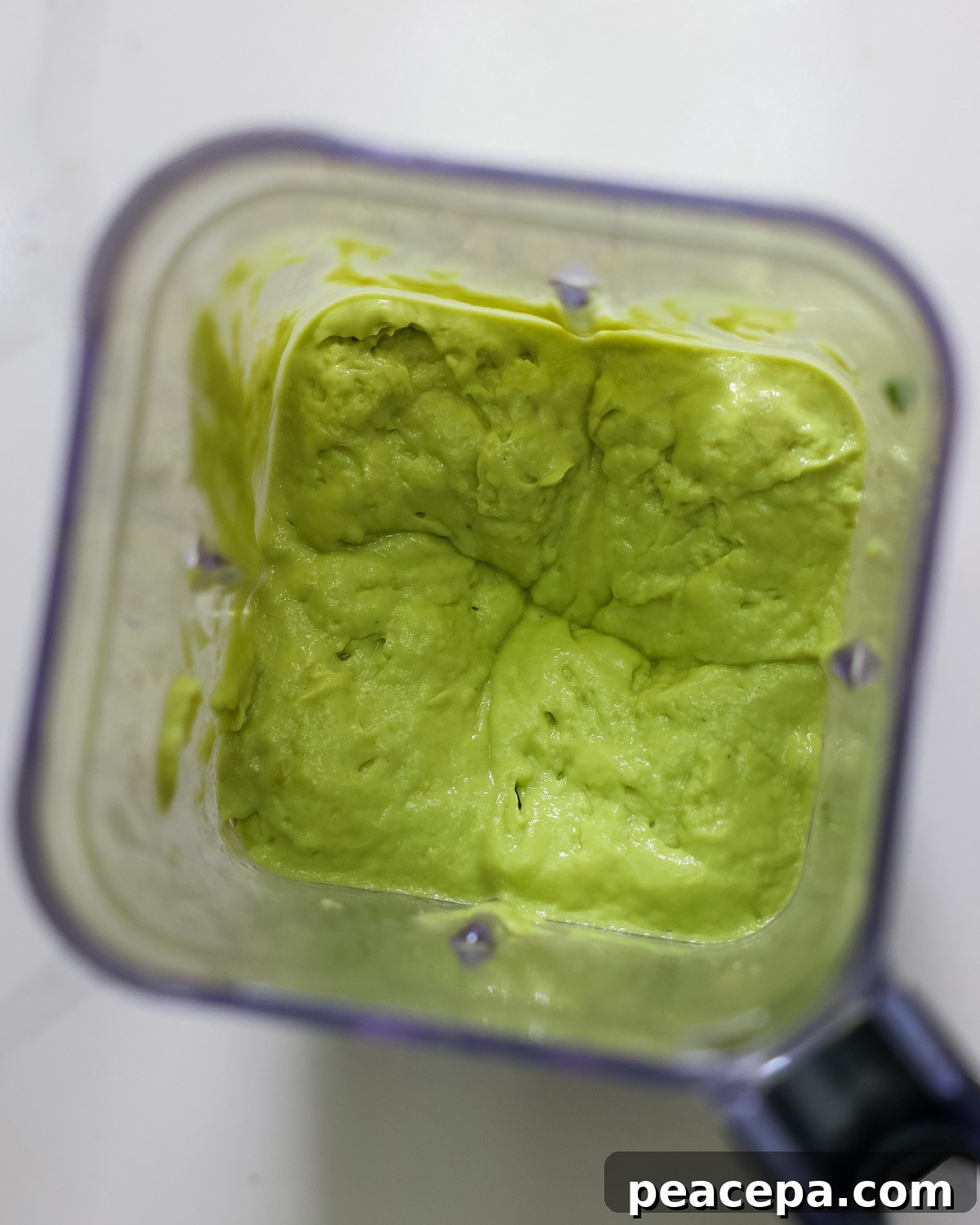 An overhead shot of a blender full of the avocado and pineapple popsicle mixture.