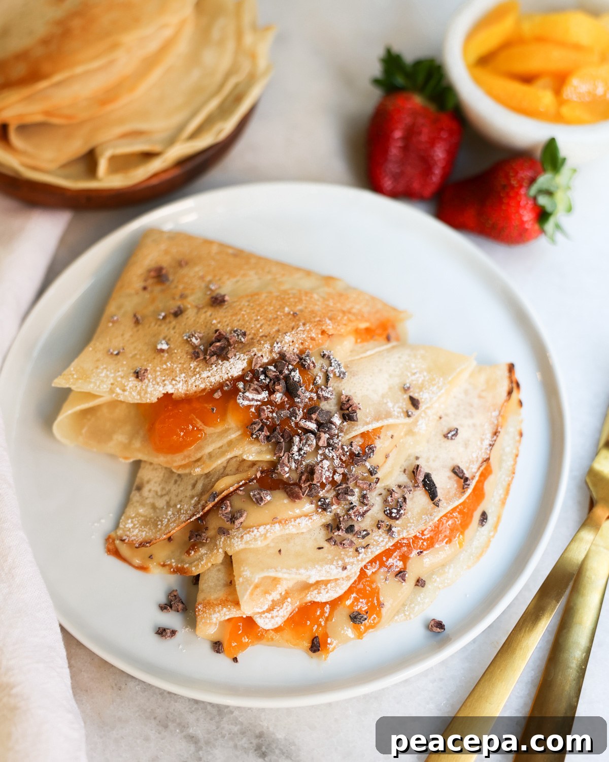 overhead of vegan crepes on a plate with peach jam