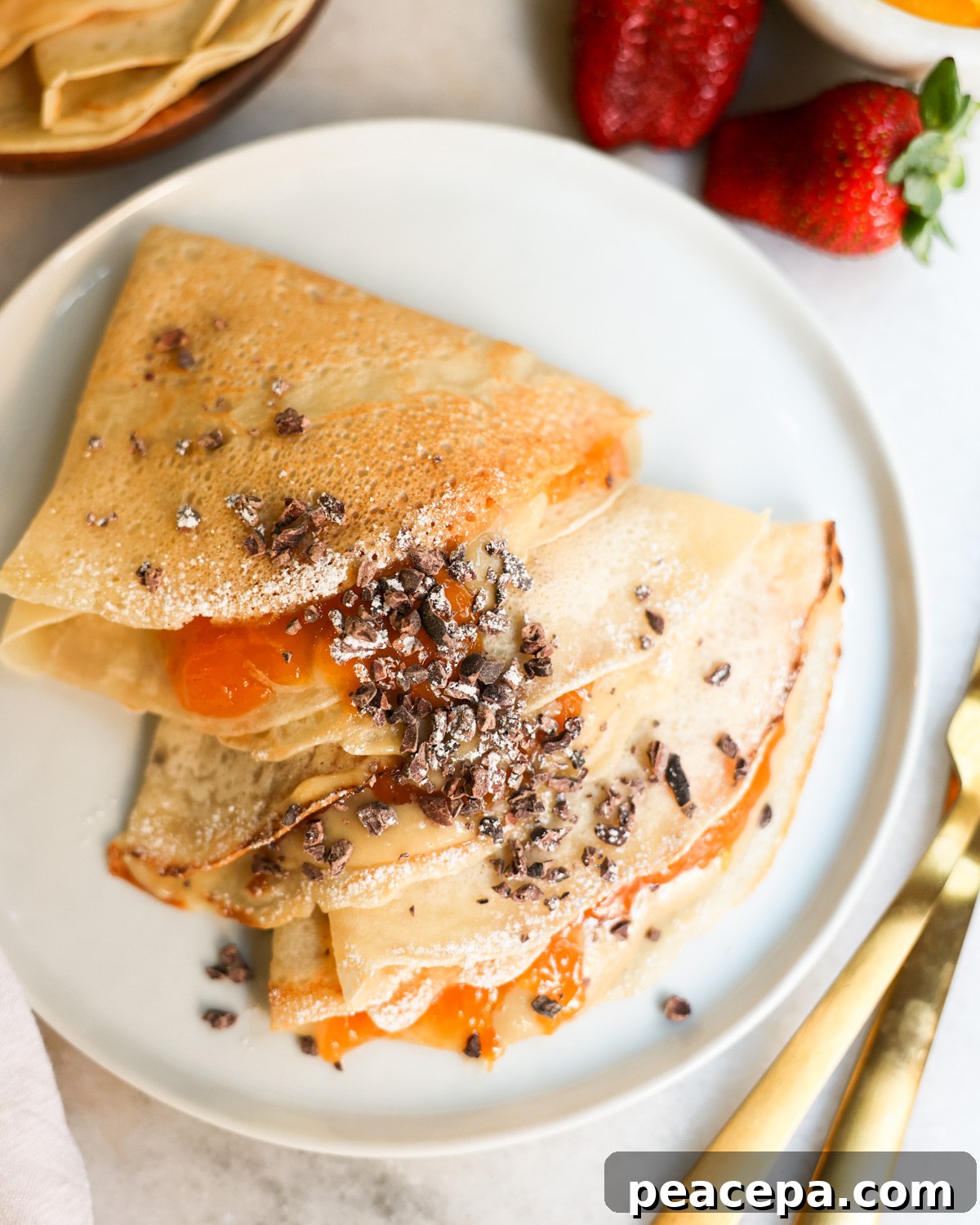 vegan crepes on plate topped with jam and powdered sugar