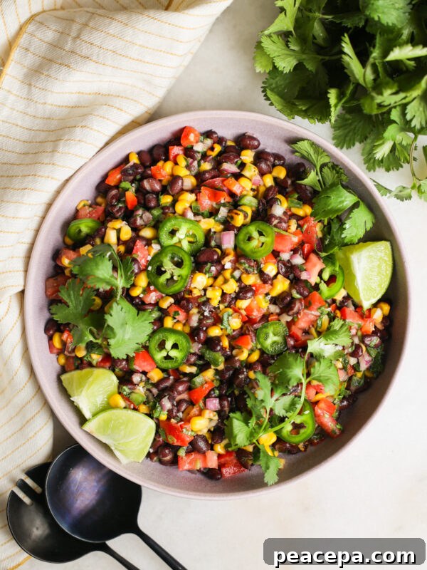 An overhead shot of a bowl of black bean and corn salad with lime, cilantro, and jalapenos.