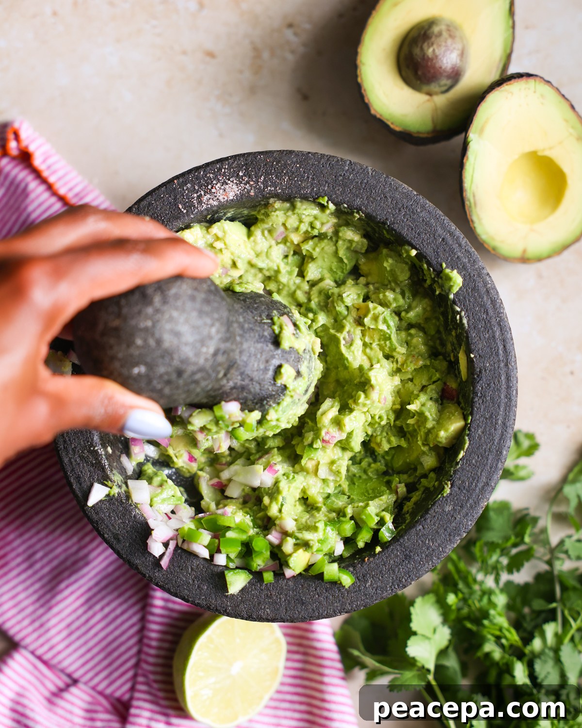 Creamy Homemade Guacamole Recipe for Parties and Dips 6 Mashing guacamole in a bowl.