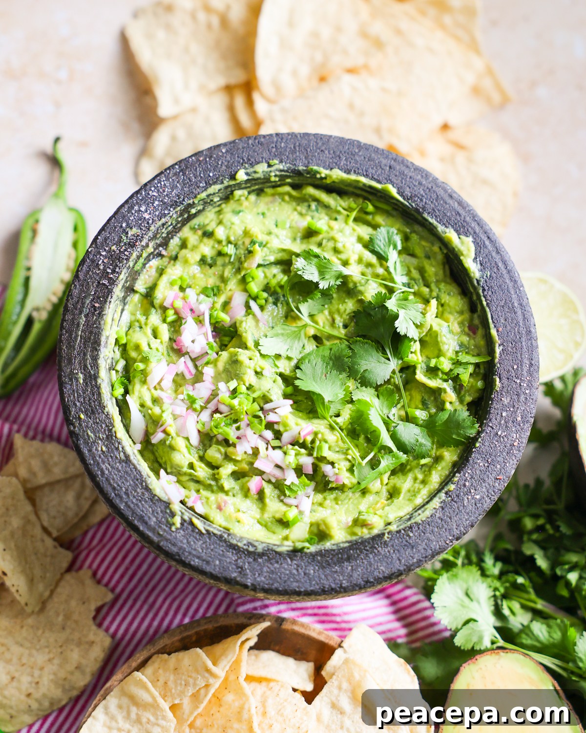 Creamy Homemade Guacamole Recipe for Parties and Dips 10 Guacamole garnished with cilantro and red onions.